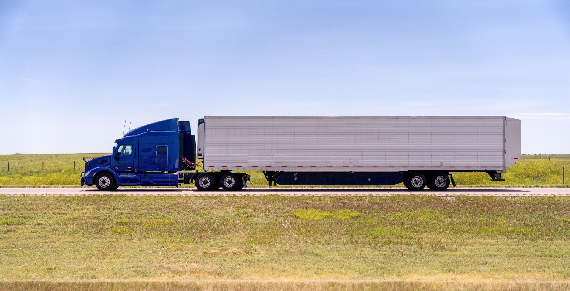 A Cloes-up View Of A Long Haul Semi Truck Speeding Down a Four Lane Highway